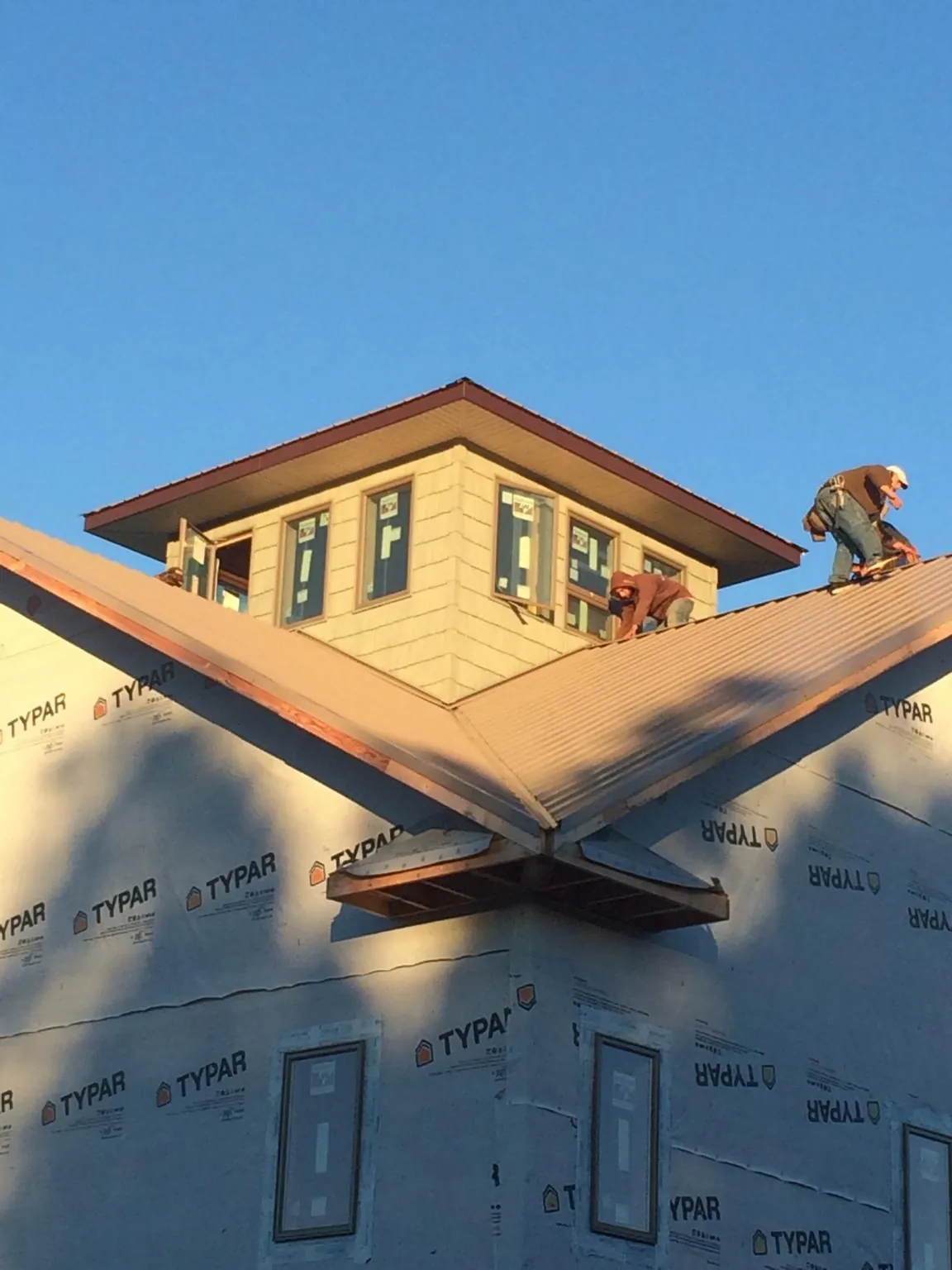 Roofers working around a rooftop cupola on a new metal roof at sunset — Roof Waterproofing in Caldwell by Roofing Brothers